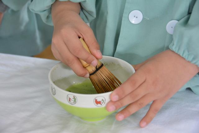茶筅でお茶を点てている園児の手のアップの写真