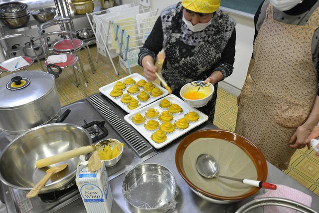 (写真)ペーストを乗せたスイートポテトに卵黄を塗る様子