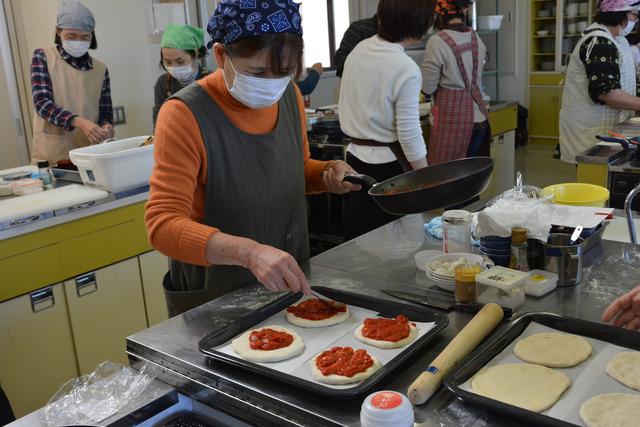 生地にトマトソースを塗っている参加者の写真