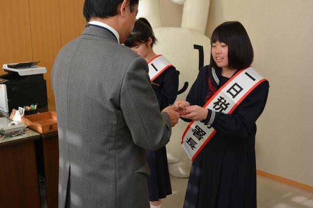 平賀さんが、一日税務署長のたすきをかけて名刺交換を行っている写真