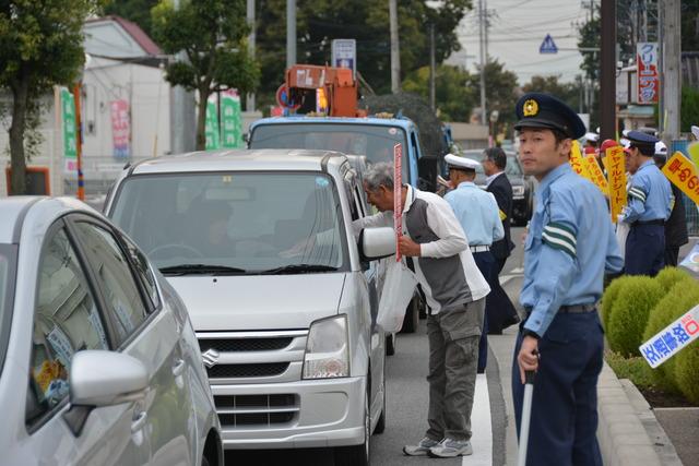 車の運転手に交通安全を呼びかけている様子の写真