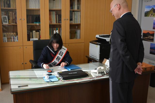 税務署長の席に座り書類に目を通す平賀さんの写真