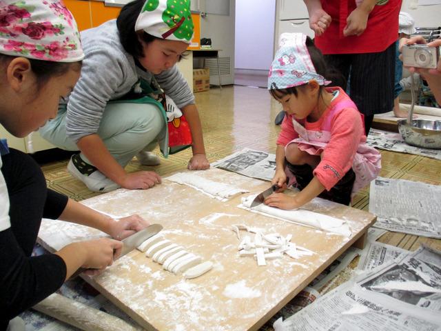 折り重ねた生地を包丁で切っている子どもたちの写真