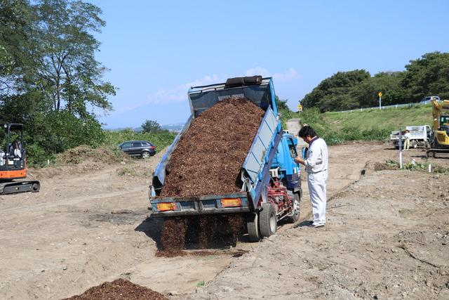 トラックに積んでいる木製チップを降ろしている写真