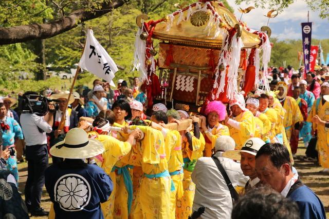 黄色の浴衣を着た男性たちが神興をかつぐ様子の写真