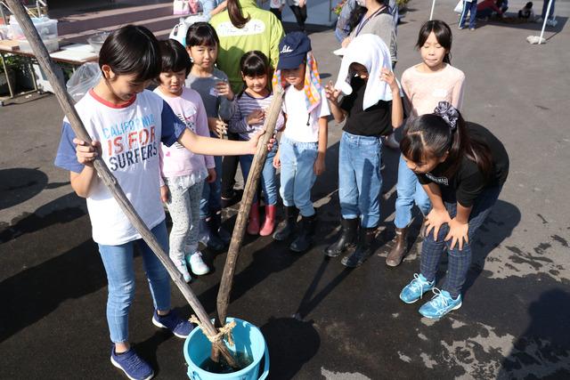 収穫したいもをみんな棒で洗っている写真