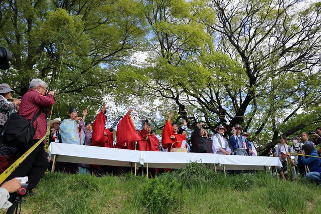 「水神」と書かれた小石を川に投げ、水防を祈願する様子の写真