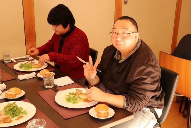 食事中の男性がvサインをしている写真