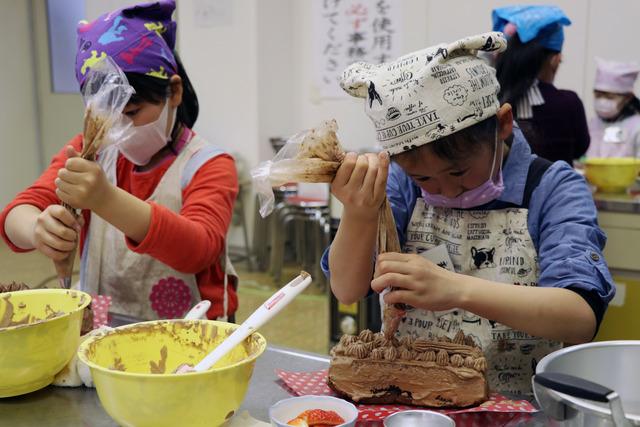 ケーキをチョコレートクリームでデコレーションしている写真