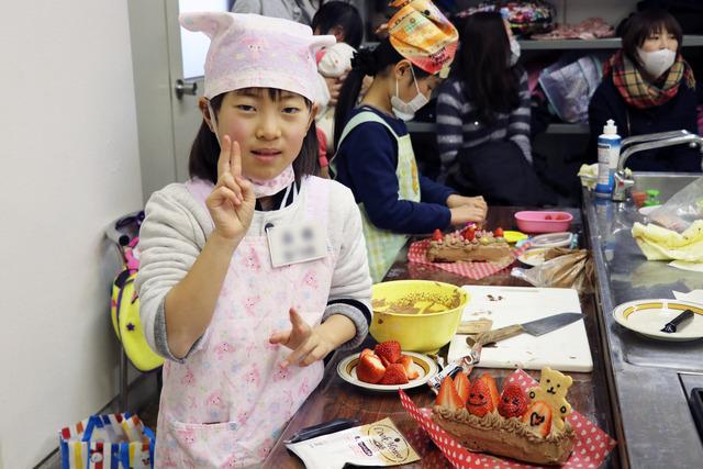 かわいくデコレーションされたケーキとピースサインの女の子の写真