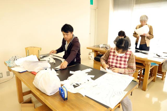 それぞれの机で図面の切り取り作業を行う参加者たちの写真