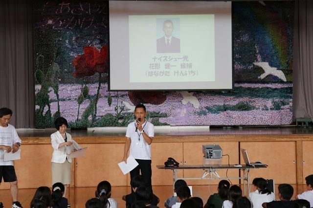竜王西小学校の体育館にて先生たちがプロジェクタを使い話をしている写真