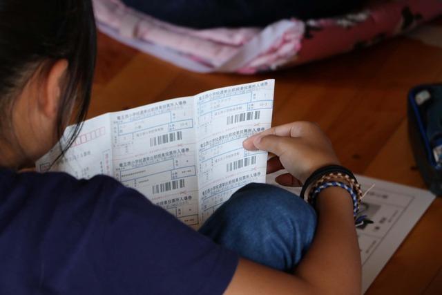 竜王西小学校の体育館にて6年生の女子児童が投票所入場券を見ている写真