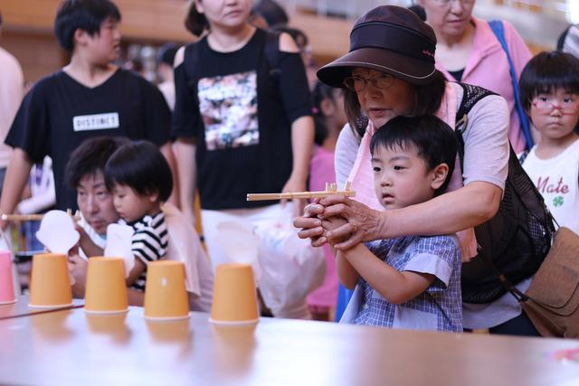 (写真)割り箸で作られた銃で射的をする子どもたち