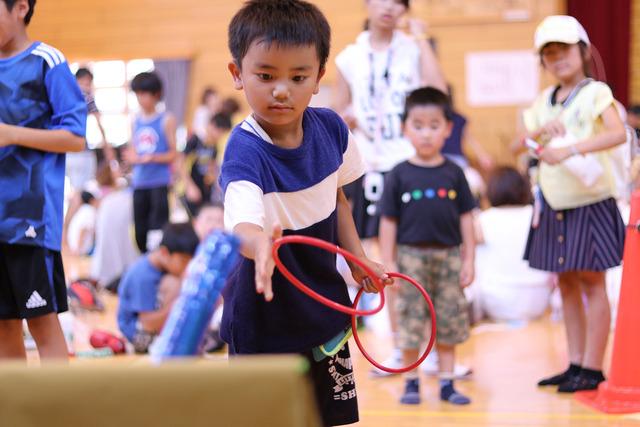 (写真)真剣な表情で輪投げをする男の子