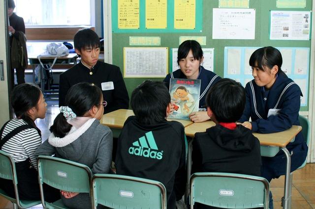 中学生が小学生に絵本を読んでいる写真