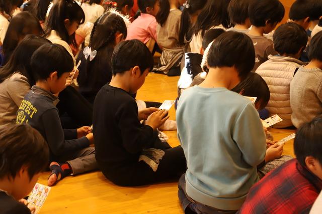子どもたちがビンゴゲームのカードを手に持って見つめている写真