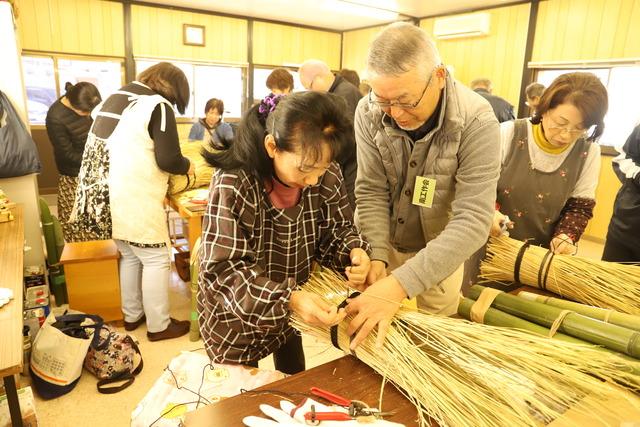 土台となる缶のまわりにわらを巻きつけている様子の写真