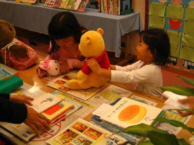 ぬいぐるみを迎えに来た子どもたちが図書館で本を借りている様子の写真