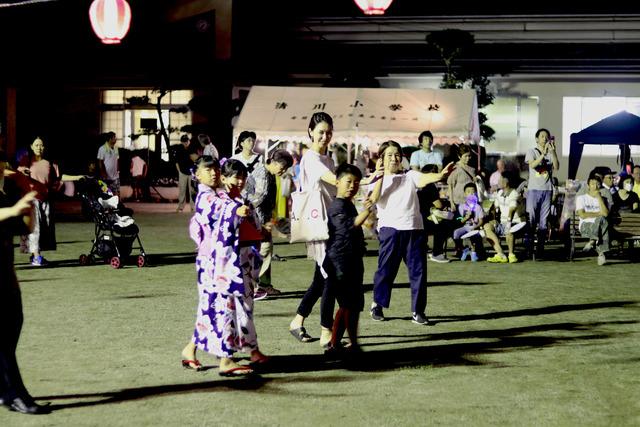 楽しそうに盆踊りを踊る子どもや大人の写真