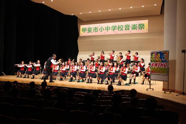 赤い衣装を着て演奏する敷島南小学校吹奏楽部の写真
