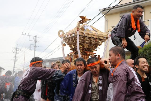 神輿を担ぐ人々に水がかけられている写真