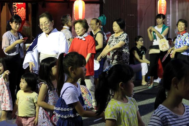 大人と一緒に盆踊りを踊る子どもたちの写真