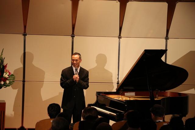 竜王図書館にてピアニストの田尻洋一さんが舞台で話をしている写真