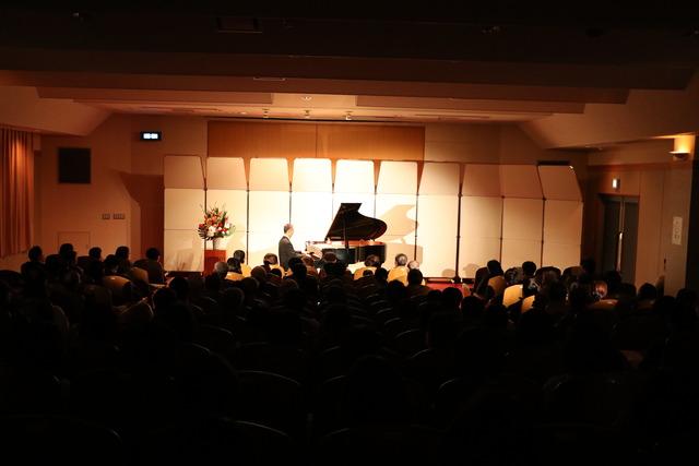 竜王図書館にて行われたピアノコンサートにて演奏する田尻洋一さんと会場全体の写真