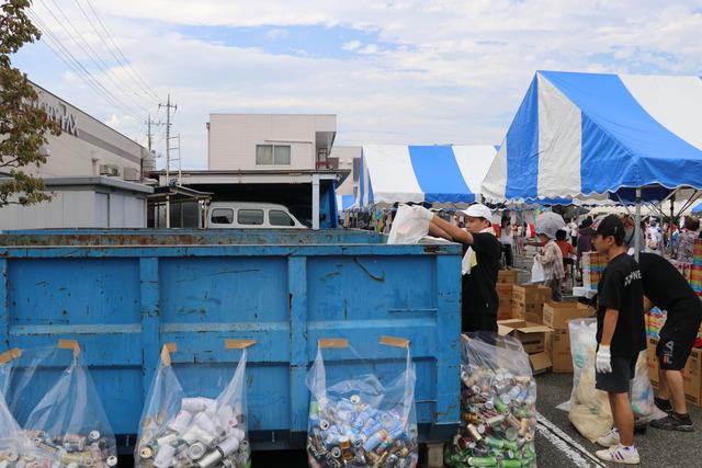 空き缶やペットボトルをビニール袋に回収している写真