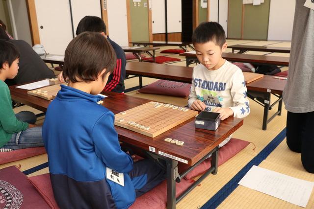 真剣なまなざしで将棋盤を見つめる二人の男の子の写真