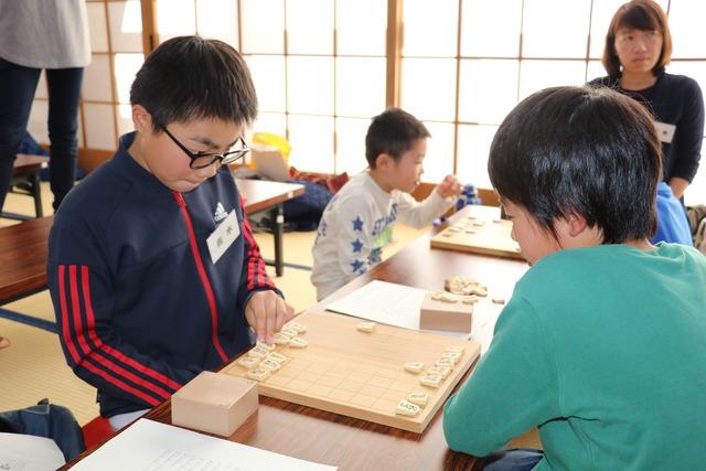 真剣な表情で駒を動かす男の子の写真