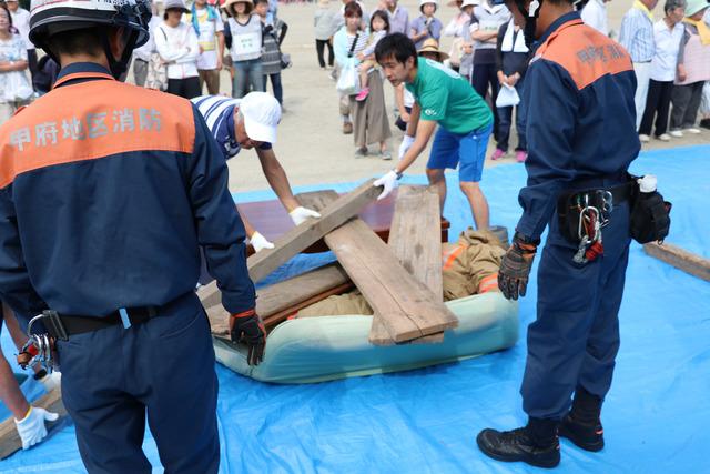 男性2人が積み重なった木材を協力して移動させている写真