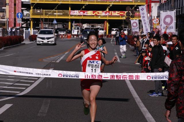 女性の選手が笑顔でVサインをしてゴールする写真