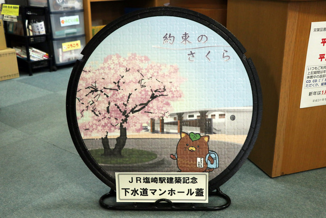 塩崎駅舎前の桜の絵柄が印刷された「約束のさくらマンホール」の写真
