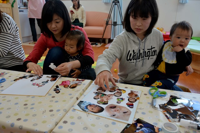 それぞれ小さな子どもを抱きスクラップブッキングを作成している二人の参加者女性の写真