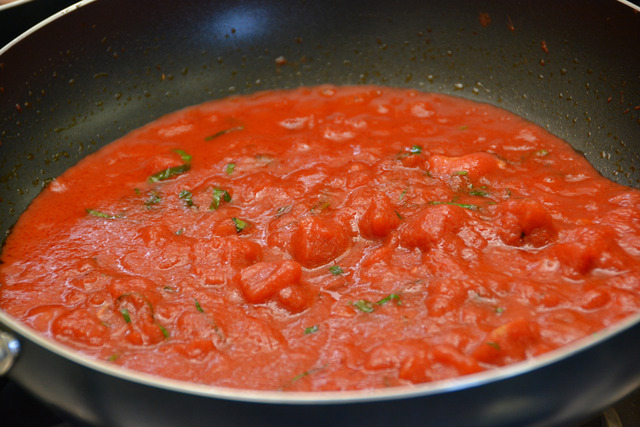 フライパンでトマト缶を入れて、煮込んでいる写真