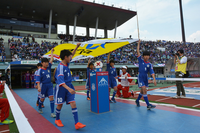 旗を掲げる竜北サッカースポーツ少年団たちの写真