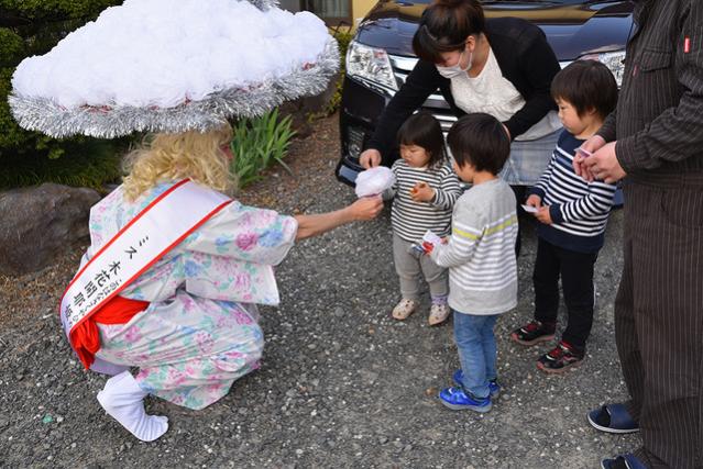 化粧コンテストの参加者が、地域の子供に花を渡している様子の写真