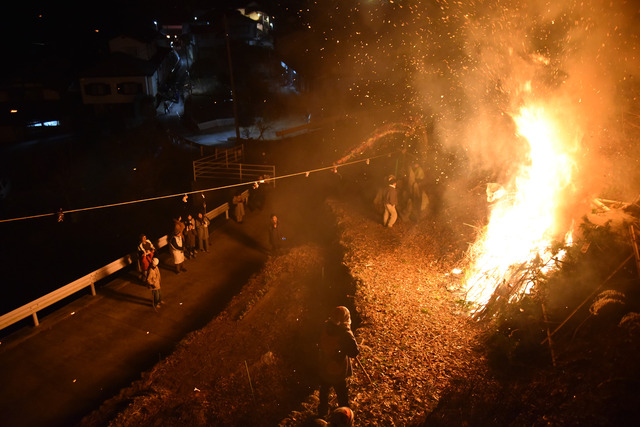 燃え上がる炎とそれを見守る住民の写真