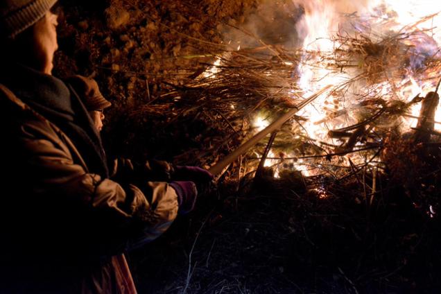 燃え上がる炎を見つめる住人の写真