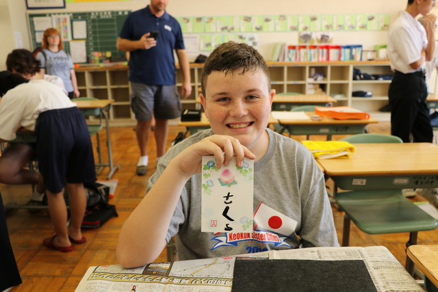自分が書いた日本語のカードを笑顔で持つキオカック市の生徒の写真