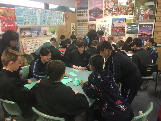 教室で、現地の学生たちに折り紙を教える訪問団のメンバーの写真