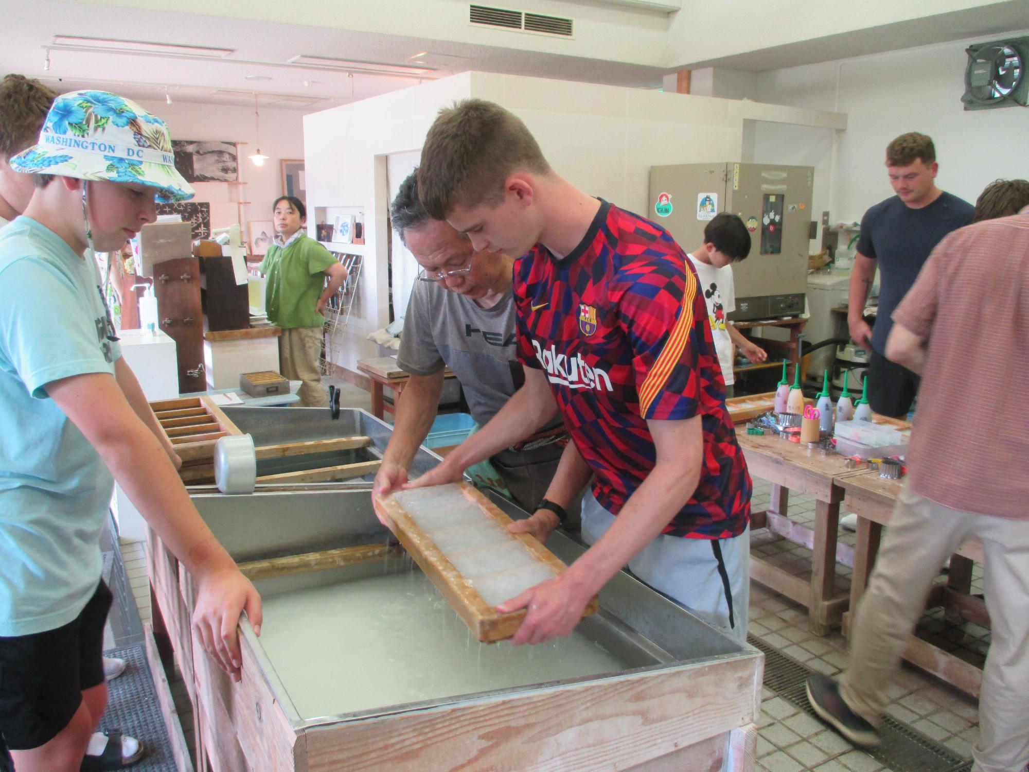 団員が紙漉き体験をしている写真