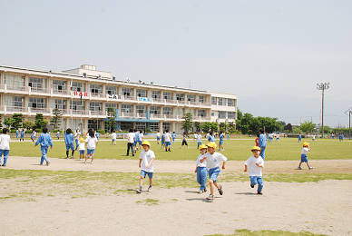 運動場で走り回る児童たちの写真