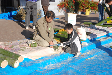 竹をノコギリで切る親子の写真