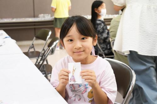 出来上がったアクセサリーを見せる子どもの写真