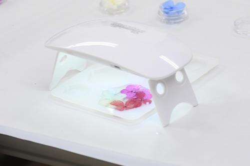 ドライフラワーが入ったレジンに光を当て硬化させている写真