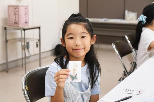 完成したレジンアクセサリーを見せる子どもの写真