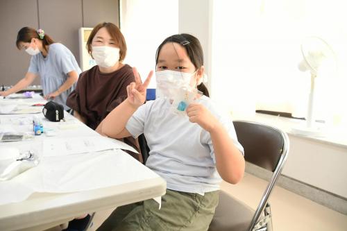 完成したアクセサリーを見せピースする子ども